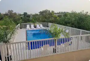 בריכת שחייה על גג עם גדר בטיחות ונוף ירוק מרהיב.