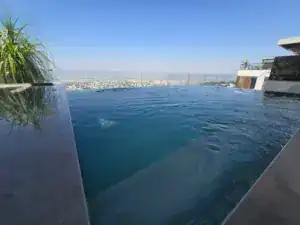 בריכת אינפיניטי על גג בניין יוקרתי עם נוף לים.